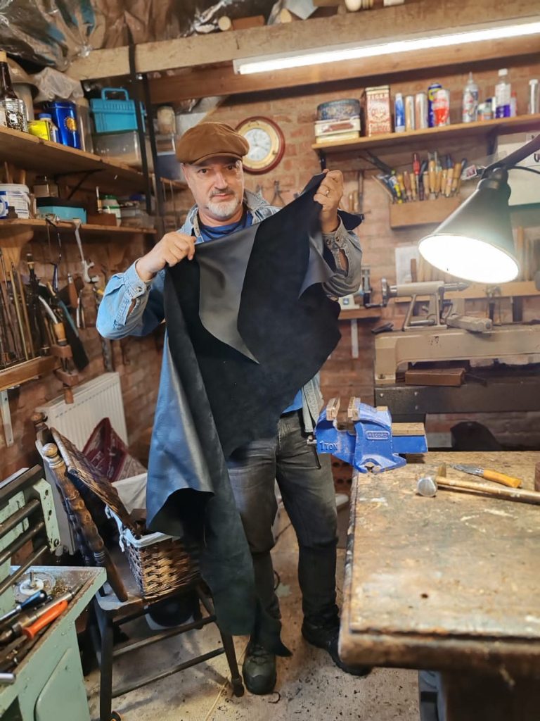 Jaff holding up a piece of leather to be used on a bag